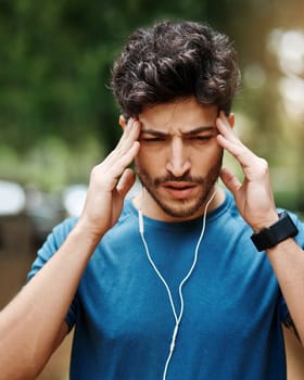 I have to focus for this one. a sporty young man suffering with a headache while exercising outdoors