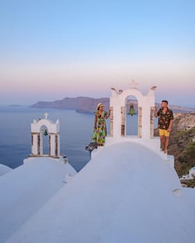 Couple watching the sunset on vacation in Santorini Greece, men and women watching the village with white churches and blue domes in Greece. 