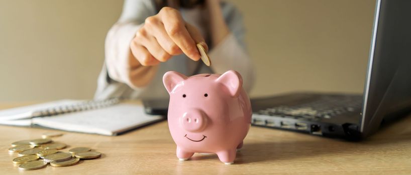 A young girl makes calculations, checks her finances, makes notes in a notebook and sets aside some of the funds, savings in a piggy bank for personal expenses and future development.