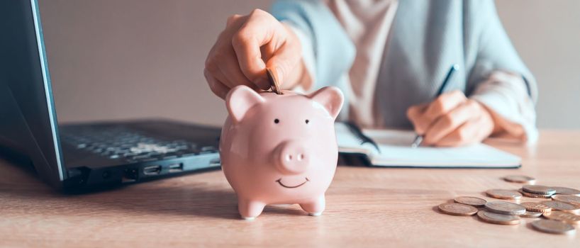 A young girl works at a laptop, writes a business development plan in a notebook, develops a strategy and makes calculations of earned funds. A woman puts her savings in a piggy bank.