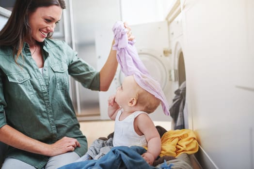 Youre not laundry. a baby girl sitting in a laundry basket while her mother does the washing