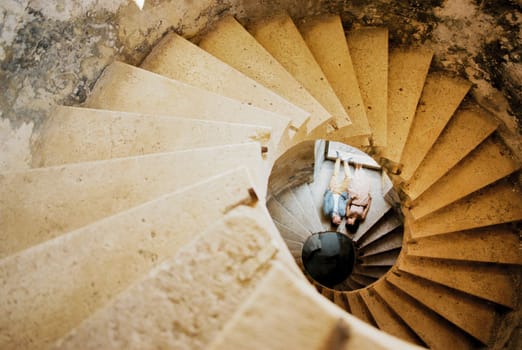 Bride and groom lie at the base of the spiral staircase. Top view. High quality photo