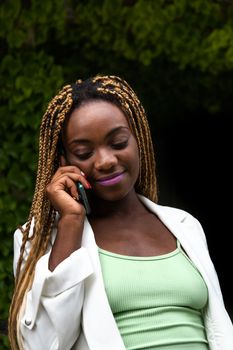 Happy Young Black woman talking on the phone outdoors.Vertical image. Lifestyle and technology.