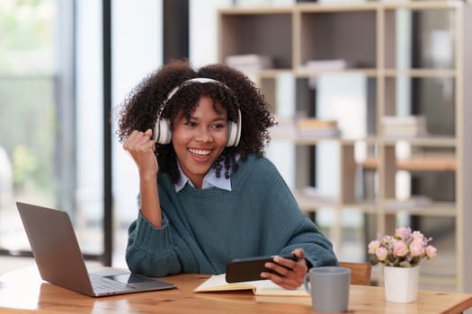 Excited Young black African woman wear headphone and enjoy with game via app on mobile phone