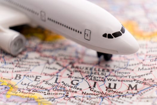 Close up of a miniature passenger plane on a colorful map highlighting Belgium through selective focus, background blur. High quality photo