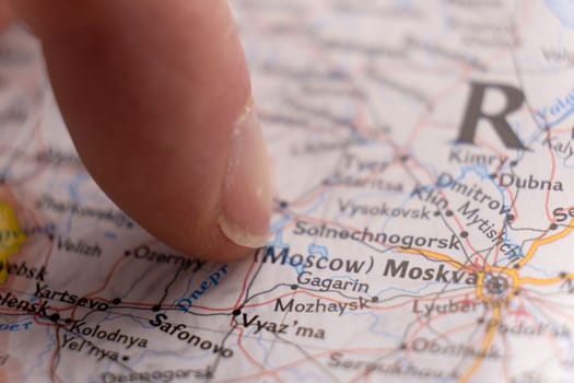 Close up of finger pointing to Moscow, Russian on colorful map with selective focus, shallow depth of field, background blur. High quality photo