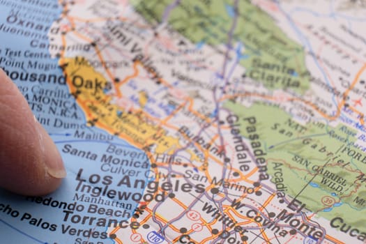 Close up of finger pointing to Los Angeles, California on colorful map with selective focus, shallow depth of field, background blur. High quality photo