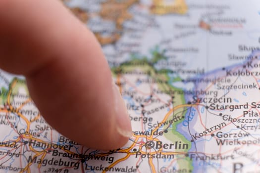 Close up of finger pointing to Berlin, Germany on colorful map with selective focus, shallow depth of field, background blur. High quality photo