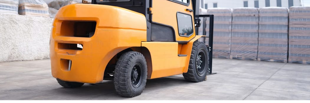 Reliable yellow forklift in warehouse. Worker ready to load pallets with skid steer loader concept