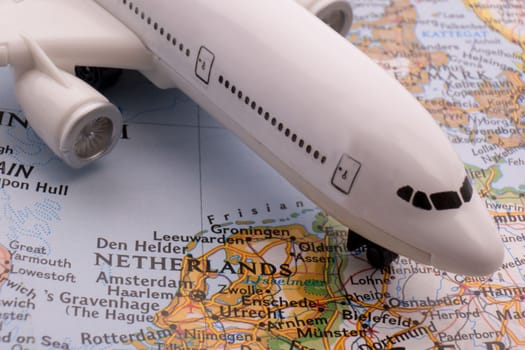 Close up of a miniature passenger plane on a colorful map showing Amsterdam, Netherlands through selective focus, background blur. High quality photo