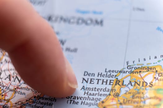 Finger pointing to Amsterdam, Netherlands on colorful map with selective focus, shallow depth of field, background blur. High quality photo