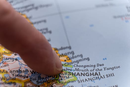 Finger pointing to Shanghai, China with shallow depth of field, background blur. Concept geopolitics. High quality photo