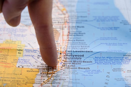Close up of finger pointing to Miami, Florida with shallow depth of field, background blur. Concept geopolitics. High quality photo