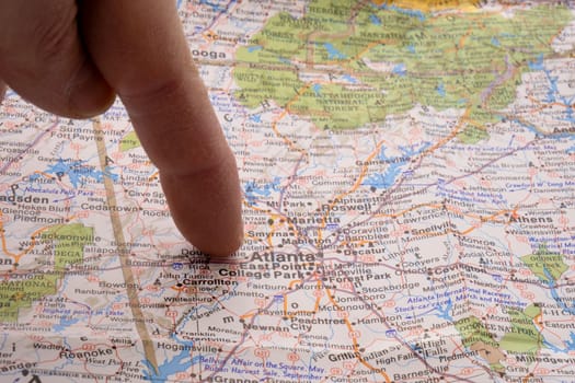 Close up of finger pointing to Atlanta, Georgia on colorful map with shallow depth of field, background blur. Concept geopolitics. High quality photo