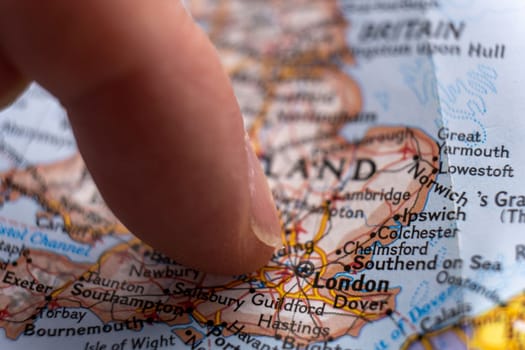 Close up of finger pointing to London, England on colorful map with selective focus, shallow depth of field, background blur. High quality photo