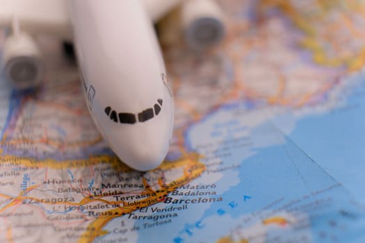 Close up of a miniature passenger plane on a colorful map highlighting Barcelona, Spain through selective focus, background blur. High quality photo