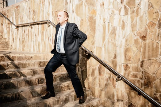 Portrait of a senior professional man in a suit with various problems. A middle-aged businessman with a briefcase descends the stairs.