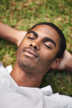 Catching a nap outdoors. a handsome young man lying on the grass outdoors