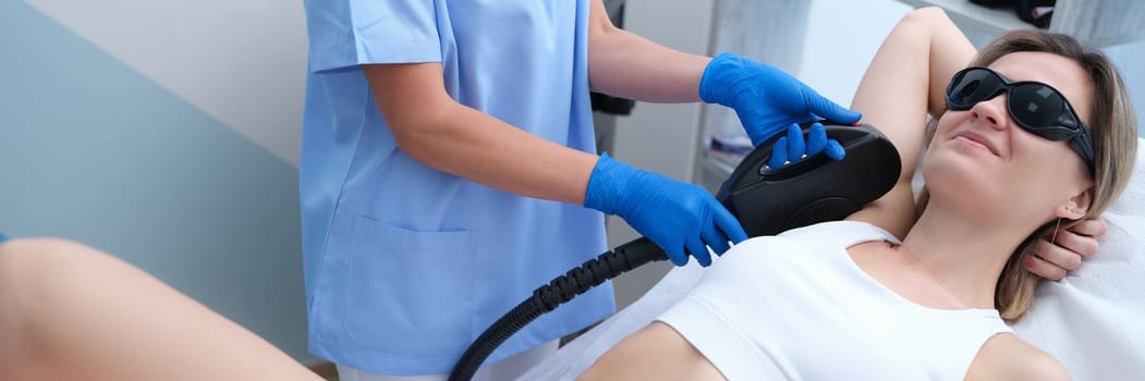 Young woman undergoes armpit laser hair removal treatment at beauty spa. Hair removal in hone armpits concept