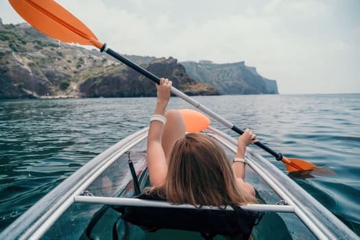 Woman in kayak back view. Happy young woman with long hair floating in transparent kayak on the crystal clear sea. Summer holiday vacation and cheerful female people having fun on the boat.