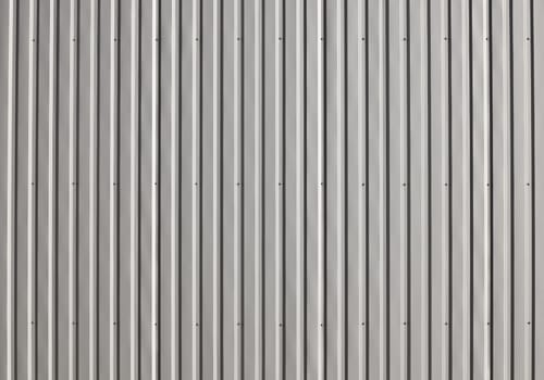 Background texture of unpainted gray aluminum corrugated goffered metal wall