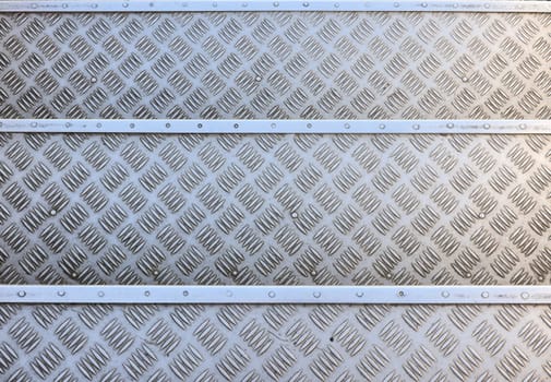 Dirty gray metal industrial anti slip embossed steel stairs with diagonal bumps of diamond pattern texture