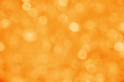 Abstract background of warm summer orange and golden bokeh defocused blurred lights and glitter sparkles