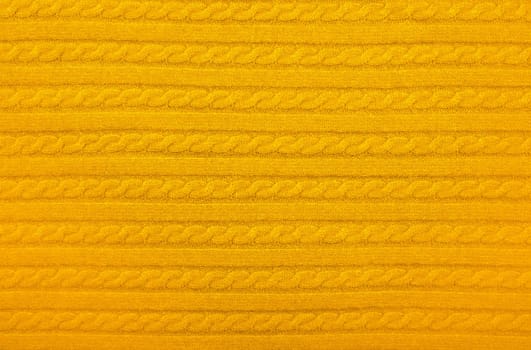 Close up background texture of warm yellow cable knitted wool jersey fabric sweater with row braid pattern