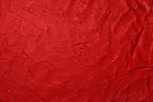 Close up vivid scarlet red abstract background texture of uneven grunge surface with brushstrokes of plaster and paint
