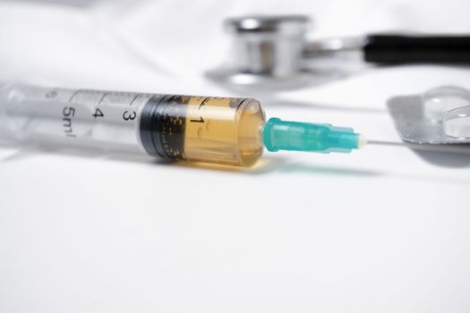 syringe, stethoscope and pills on a doctor's gown white background and copy space