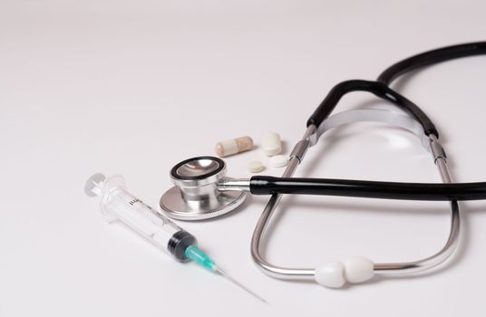 syringe, stethoscope and pills on a doctor's gown white background and copy space