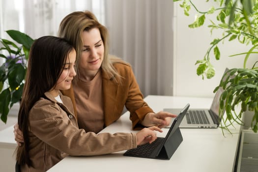 Mother and Daughter Watching into Laptop at Home. Daughter Helping Mother. Mother and Daughter at Home. Teenage Girl. Frilancing Mother Concept. Women Using Digital Device. Smiling Woman.