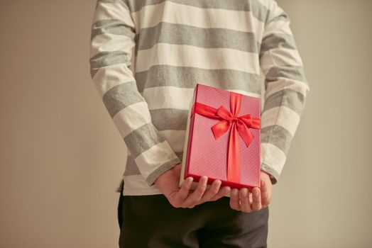 Man standing and holding red gift box behind his back