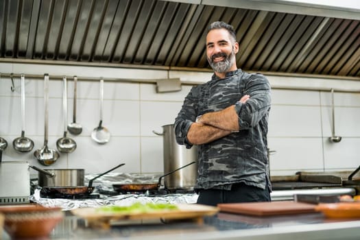 Professional cook is ready for preparing meal in restaurant's kitchen.