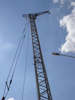 Abstract Industrial background with construction crane on blue sky. Construction site art. Crane and building working progress. Empty Space for text. Construction concept. New buildings with a crane.