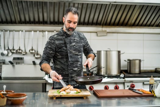 Professional cook is preparing meal in restaurant's kitchen.