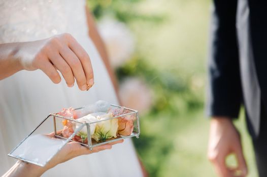 The groom puts an engagement ring on the bride's finger on their wedding day.