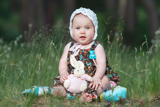 cute girl sitting on the spring grass with a toy , baby