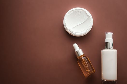 Skincare cosmetics and anti-aging beauty products, luxury skin care bottles, oil, serum and face cream on brown background.