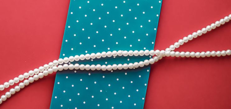Pearl jewellery necklace and abstract blue polka dot background on coral backdrop.