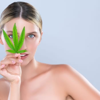 Alluring beautiful woman model portrait holding green leaf as concept for cannabis skincare cosmetic product for skin freshness treatment in isolated background.