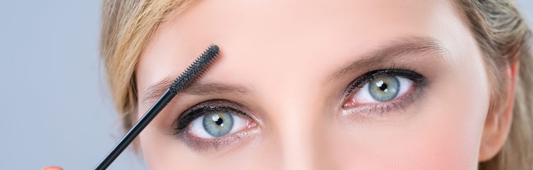 Closeup woman with blond hair putting alluring black mascara with brush in hand on long thick eyelash. Perfect fashionable cosmetic clean facial skin with beautiful eye young woman in high resolution.