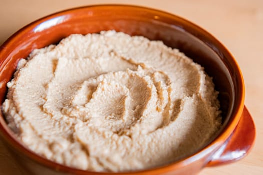 Home made hummus in a bowl on a wooden table.
