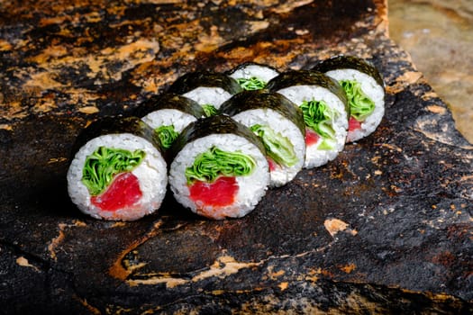 This appetizing photo showcases a sushi roll that is sure to make your mouth water. The roll is expertly crafted and features fresh ingredients, including rice, seaweed, and a variety of tasty fillings. The sushi is elegantly arranged on a stone plate, which contrasts nicely with the vibrant colors of the roll. The photo is perfect for anyone looking to add a touch of sophistication and culinary flair to their marketing materials, blog posts, or social media accounts. Whether you are a food blogger, restaurant owner, or just a lover of sushi, this photo is sure to delight your audience and leave them craving more