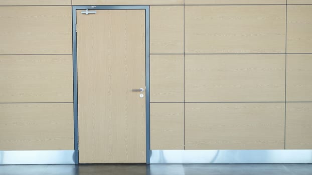 Interior of long wall with light brown door airport or train station. One stylish door in business center