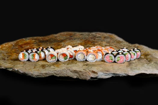 This appetizing photo showcases a sushi roll that is sure to make your mouth water. The roll is expertly crafted and features fresh ingredients, including rice, seaweed, and a variety of tasty fillings. The sushi is elegantly arranged on a stone plate, which contrasts nicely with the vibrant colors of the roll. The photo is perfect for anyone looking to add a touch of sophistication and culinary flair to their marketing materials, blog posts, or social media accounts. Whether you are a food blogger, restaurant owner, or just a lover of sushi, this photo is sure to delight your audience and leave them craving more