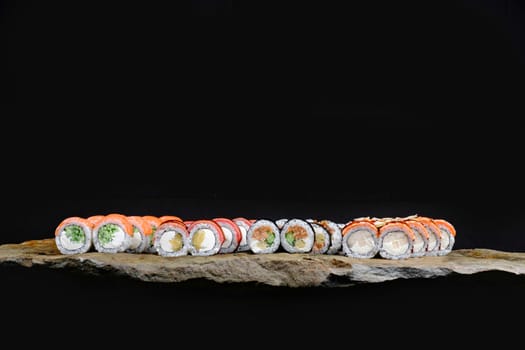 This appetizing photo showcases a sushi roll that is sure to make your mouth water. The roll is expertly crafted and features fresh ingredients, including rice, seaweed, and a variety of tasty fillings. The sushi is elegantly arranged on a stone plate, which contrasts nicely with the vibrant colors of the roll. The photo is perfect for anyone looking to add a touch of sophistication and culinary flair to their marketing materials, blog posts, or social media accounts. Whether you are a food blogger, restaurant owner, or just a lover of sushi, this photo is sure to delight your audience and leave them craving more