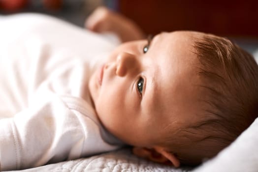Everything is brand new to babies. an adorable baby boy lying down on a bed at home