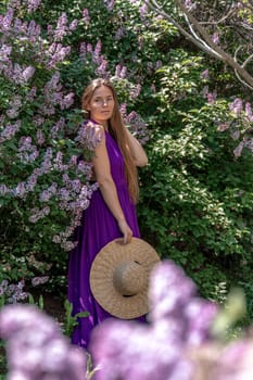 portrait of young woman with long hair outdoors in blooming lilac garden.