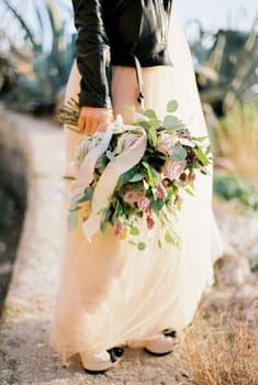 Bouquet of flowers in the hand of a bride in a leather jacket. High quality photo